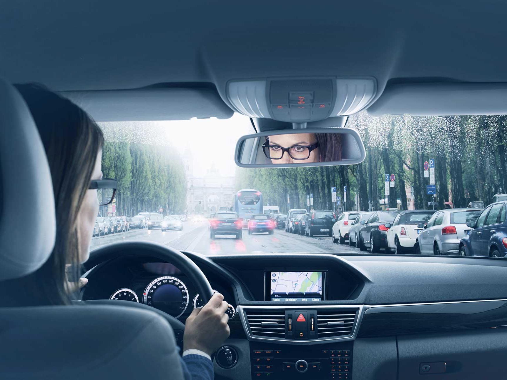 Imagen del interior de un vehículo con una mujer sentada en el asiento del conductor. 