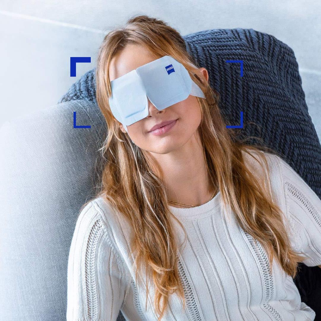 Mujer que usa una ZEISS Warm Eye Mask y se la ve relajada en una silla.