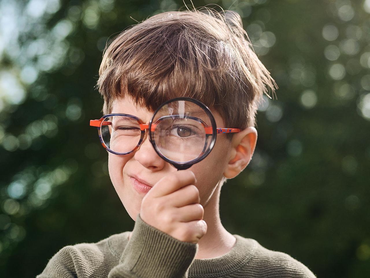 Niño con lentes usando una lupa 