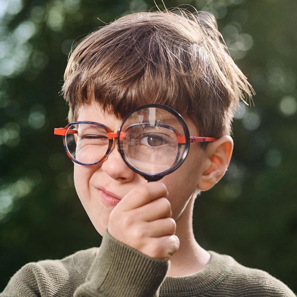 Niño con lentes usando una lupa 