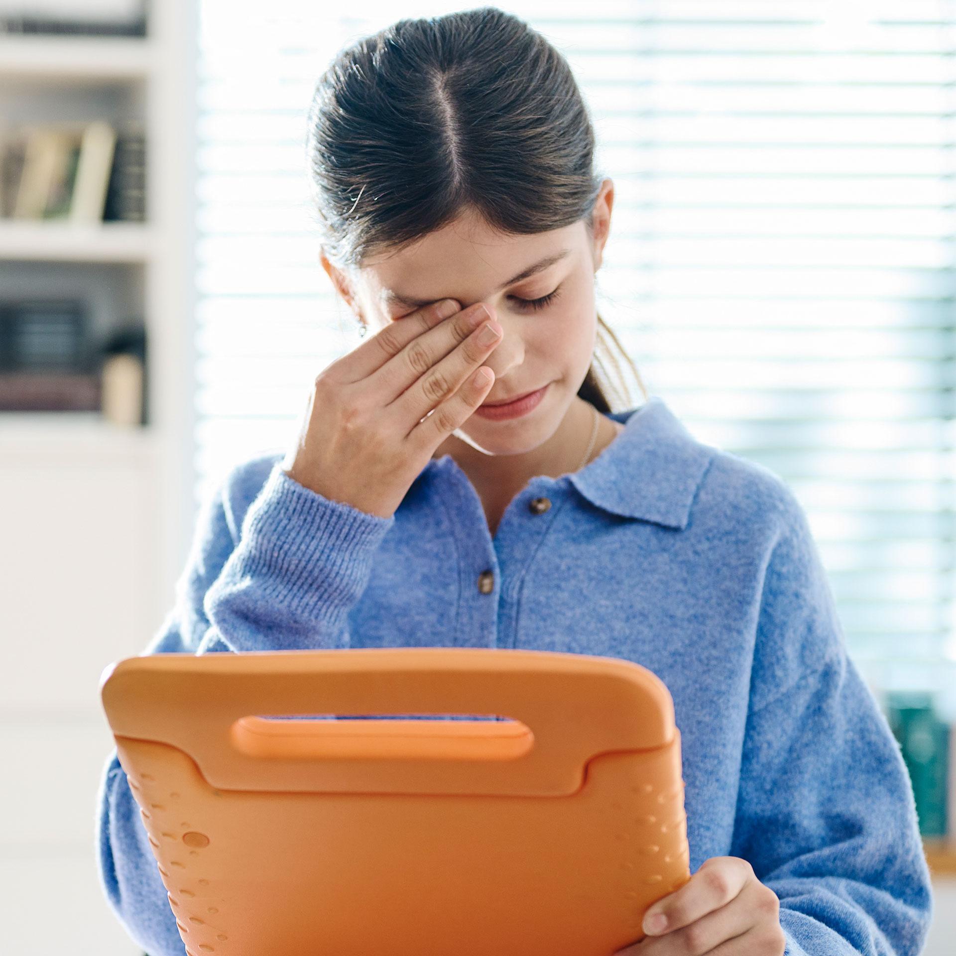 Muchacha con una tablet poniéndose la mano en la cara