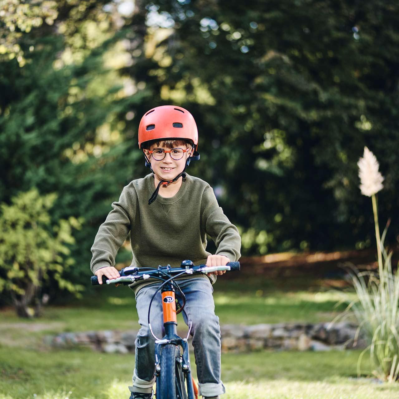 Niño con lentes montando en bicicleta al aire libre con una sonrisa