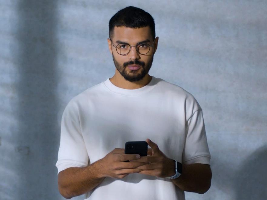 Un joven con lentes BlueGuard, ocupado con su smartphone.