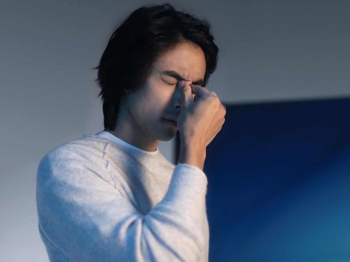 Hombre tocándose la parte interna de los ojos, luchando contra el dolor de cabeza o los ojos cansados.