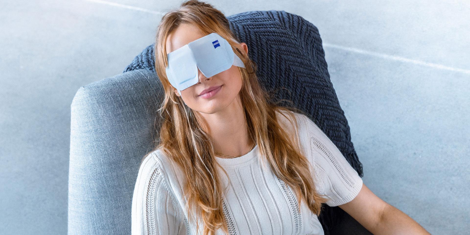 Mujer que usa una ZEISS Warm Eye Mask y se la ve relajada en una silla.